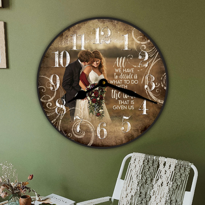 A round wall clock with a vintage-style wedding couple photo in the center, styled in a room on an olive green wall next to a white armchair and a small side table.