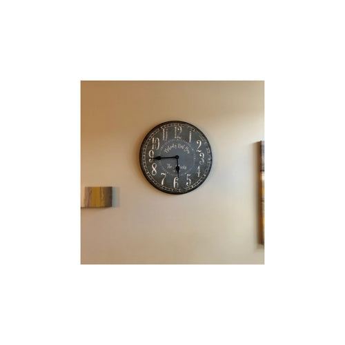 Dark personalized wall clock with white numerals displayed on a beige wall